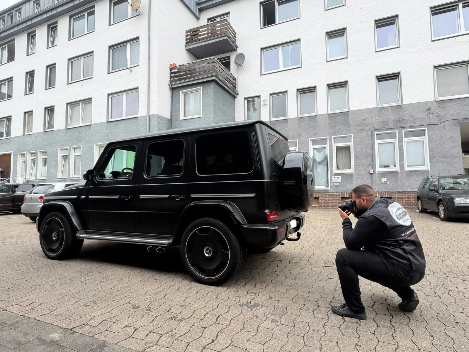 Herr Khalek fotografiert eine schwarze Mercedes G-Klasse bei der Begutachtung