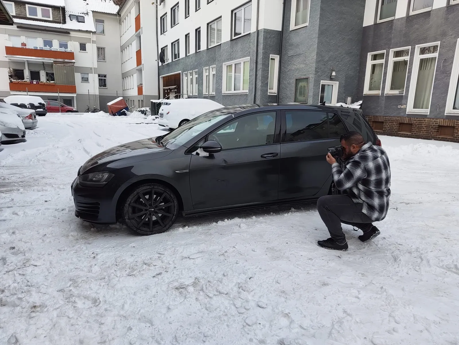 Herr Khalek fotografiert die Seite eines schwarzen VW Golf im Schnee