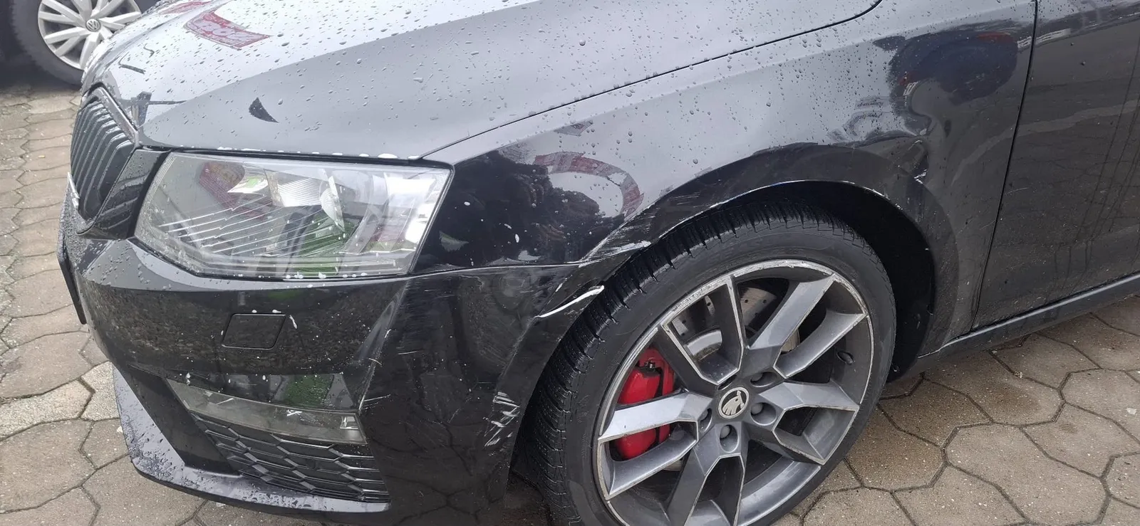 Unfallschaden an Stoßstange und Kotflügel eines schwarzen Škoda