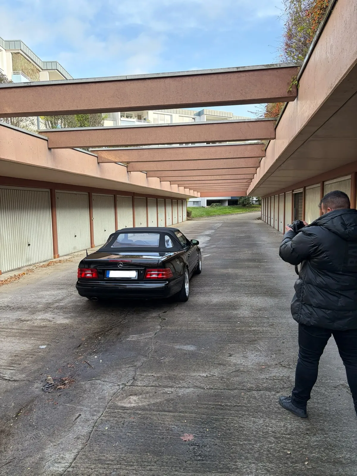 Herr Khalek fotografiert ein schwarzes Mercedes SL Cabrio im Garagenhof