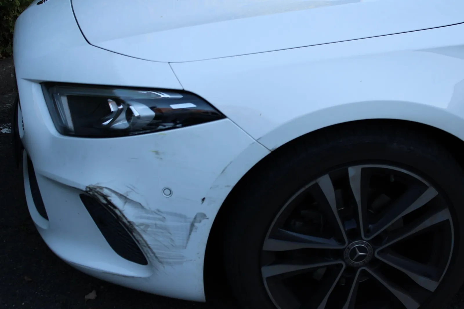Streifschaden an der Frontstoßstange eines weißen Mercedes